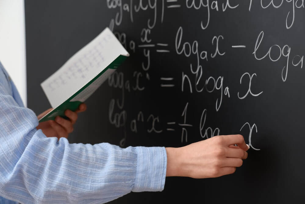 shutterstock_2807159525 insegnante di matematica scrive alla lavagna per rappresentare master materie scientifiche classi di concorso A20-26-27-28